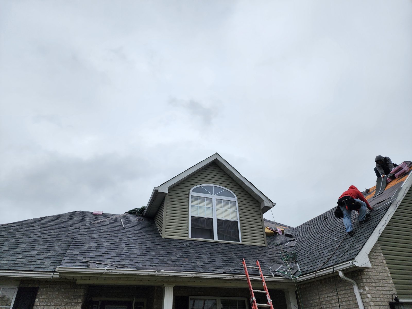 Crew installing new shingles on a steep pitch roof
